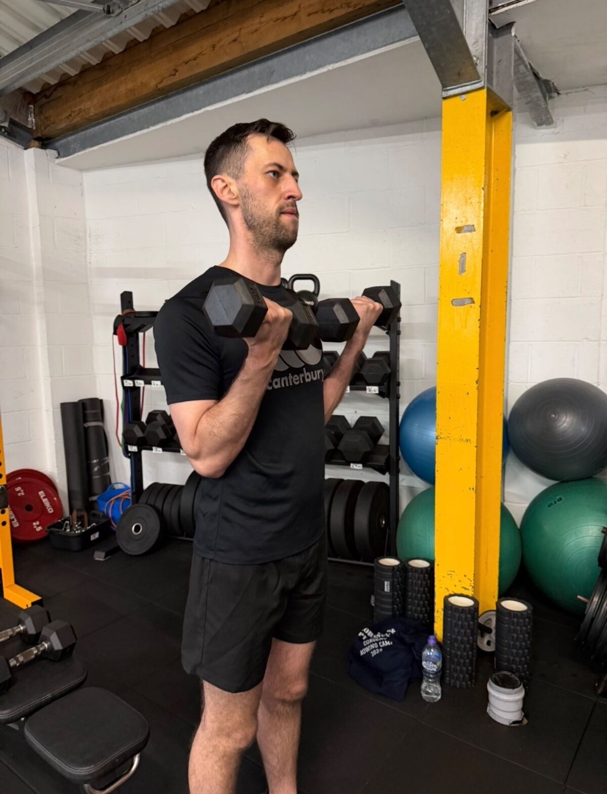 CJ White, personal trainer in Greenwich, performing a dumbbell curl in his training studio